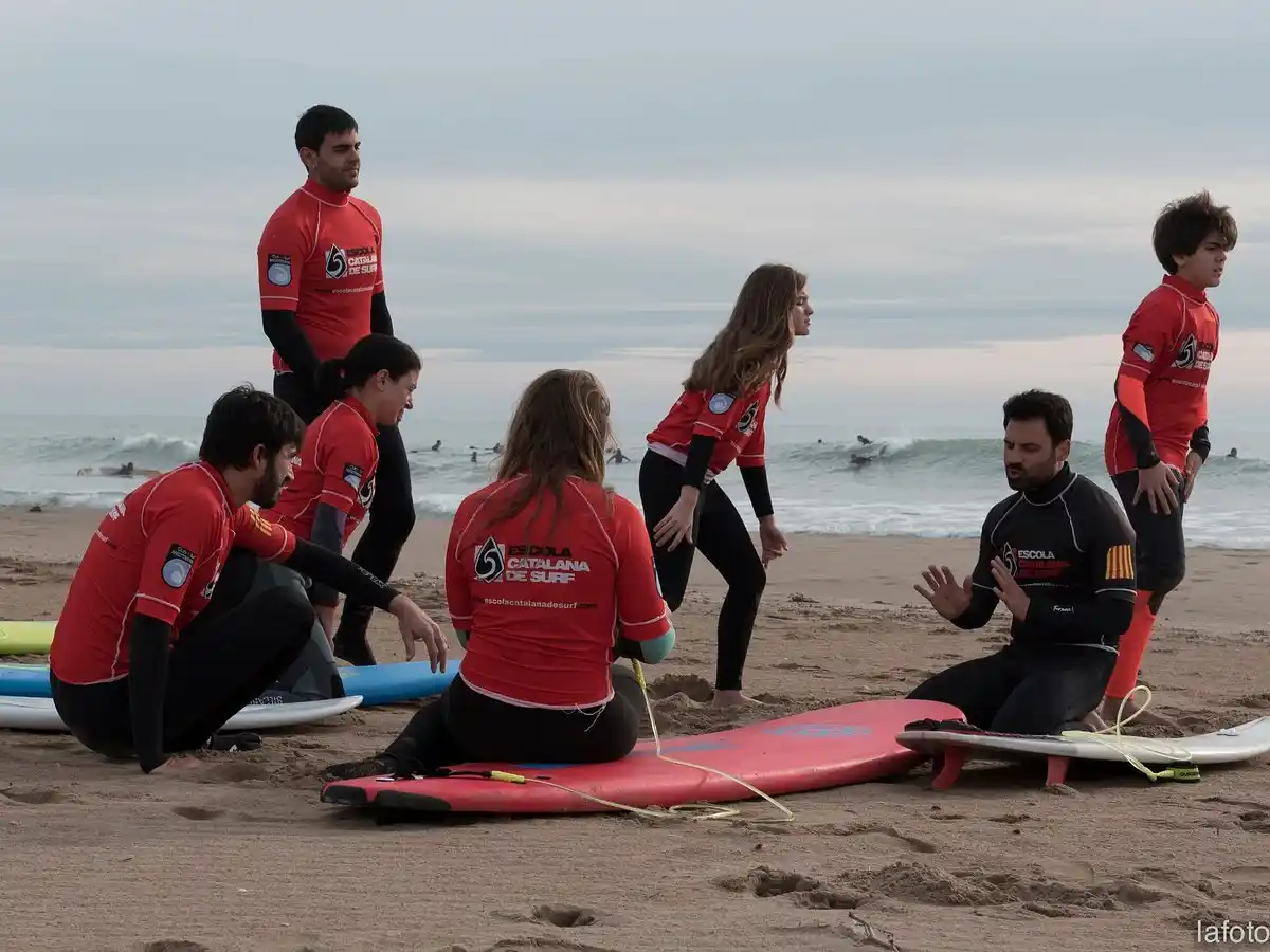 Instructor enseñando a un grupo de niños a surfear en la playa de Castelldefels, cerca de Port Ginesta.